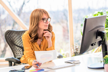 Wall Mural - Middle aged businesswoman sitting behind her computer while working from home