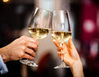 Closeup of a couple toasting white wine glasses
