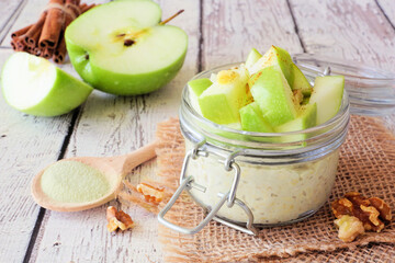 Wall Mural - overnight oats with matcha and green apples in a jar. table scene with a rustic white wood backgroun
