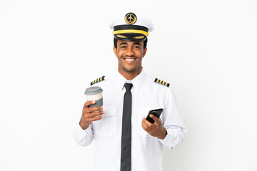 Wall Mural - African American Airplane pilot over isolated white background holding coffee to take away and a mobile