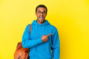 Wall Mural - African American student man over isolated yellow background surprised and pointing side