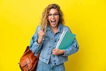 Young student caucasian woman isolated on yellow background celebrating a victory in winner position