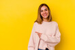 © Asier - Young caucasian skinny woman isolated on yellow background smiling and pointing aside, showing something at blank space.