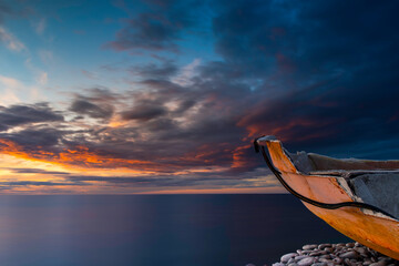 Wall Mural - Broken boat on beach with cloudy sunset background