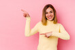 © Asier - Young caucasian woman isolated on pink background excited pointing with forefingers away.
