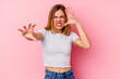 © Asier - Young caucasian woman isolated on pink background upset screaming with tense hands.
