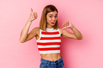 Wall Mural - Young caucasian woman isolated on pink background showing thumbs up and thumbs down, difficult choose concept