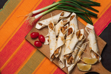 Small tacos with chicken, dipping sauces and food ingredients called taquitos