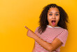 Young african american woman isolated on yellow background pointing to the side