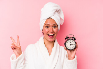 Young venezuelan woman late for work isolated on pink background joyful and carefree showing a peace symbol with fingers.