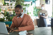 © Seventyfour - Portrait of African-American businessman using laptop while working in eco friendly cafe interior decorated with fresh green plants, copy space
