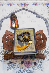 Wall Mural - Holy Quran book, rosary and arabian lantern on praying mat. Islamic Ramadan concept