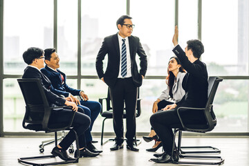 Wall Mural - Businessman coach speaker presentation and discussing meeting strategy sharing idea.Creative casual business people showing hand to answer question in conference seminar at hall.presentation