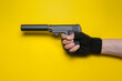A toy pistol with a silencer in the male hand isolated on yellow background.