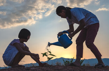 Wall Mural - Silhouette two children planting at sunset.Concept of world environment day.