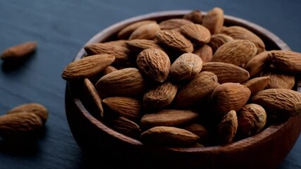 Wall Mural - Almond nut. Roasted almonds in a round wooden cup on a black slate background.Nuts and seeds closeup.Tasty snack. Healthy fats.