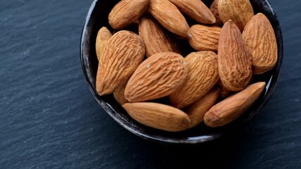 Wall Mural - Almond nut. Roasted almonds in  in a black ceramic cup close up on a black slate background.Nuts and seeds closeup.Tasty snack. Healthy fats.