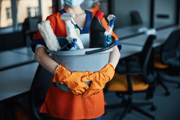 Cleaner in a face mask showing her cleaning products