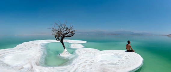 A man and a lonely tree on salt island in Dead Sea, Israel.