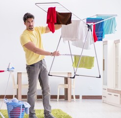 Wall Mural - Handsome man husband doing laundering at home