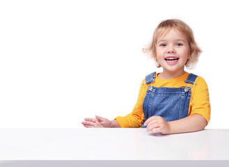 Wall Mural - Little child sitting at white table empty copy space background.