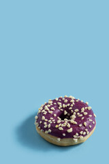 Wall Mural - Bright donut with yellow glaze and a multi-colored sprinkle on blue vertical background .Sweet minimalist food image.