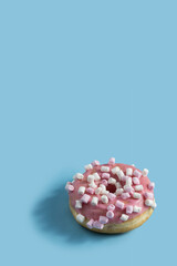 Wall Mural - Pink donut with marshmallow topping on blue vertical background .Sweet minimalist food image. Modern concept