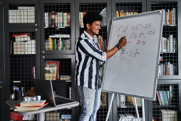 Good Indian teacher, online learning, he smiles and writes on the board, looks at the computer, online lesson