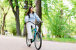 Positive woman riding blue vintage bicycle at green park