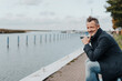 © contrastwerkstatt - Man sitting at the waterfront in a harbour looking off to the side