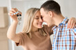 © insta_photos - Happy young couple home owners holding keys in new home. Smiling independent man and woman first time homeowners showing keys to own flat. Mortgage loan, new house ownership concept, close up view.