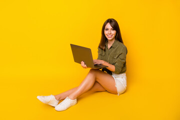 Wall Mural - Full size profile photo of pretty positive lady sit hands hold laptop toothy smile isolated on yellow color background