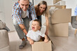 © insta_photos - Happy parents having fun playing with cute toddler kid son riding in box on moving day. Excited young couple pushing box with child boy celebrating relocation. Young family move into new home concept.