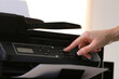 © New Africa - Woman using modern printer in office, closeup