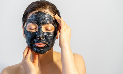 Woman relaxing with black charcoal facial mask