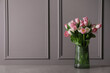 Beautiful bouquet of tulips in glass vase on grey table. Space for text