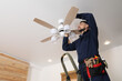 © New Africa - Electrician repairing ceiling fan with lamps indoors. Space for text