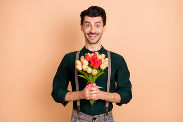 Sticker - Photo of young handsome man happy positive smile hold flowers bouquet celebration isolated over beige color background