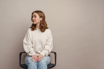 Wall Mural - Young white woman looking aside while sitting on chair