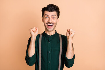 Sticker - Photo of young happy excited crazy amazed man raise fists in victory success triumph isolated on beige color background