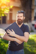 © endrews21 - Cheerful bearded male developer with a long beard and dark gray hair in a shirt and jeans hugs a laptop on the background of a green park in spring