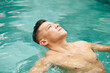 © DragonImages - Fit man floating on back in swimming pool and looking at sky