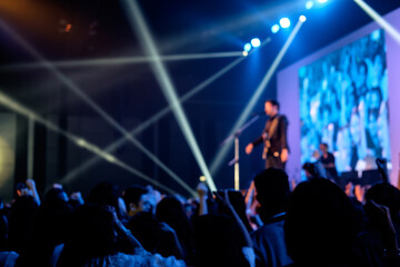 Silhouettes of people enjoying live concert of musician band performing song on stage in bright spotlights