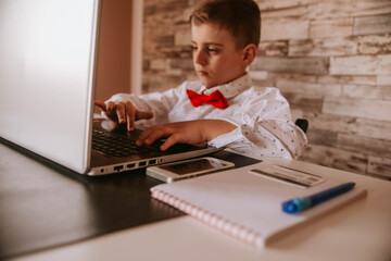 Hands of a small businessman working on a laptop. There is also a mobile phone, payment card and notebook on the table