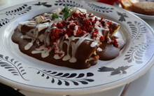 Closeup Of Mole Sauce-covered Enchiladas Dish With Red Garnish At A Luxury Resort In Mexico