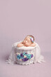 Newborn girl on a violet background. Photoshoot for the newborn.  A portrait of a beautiful newborn baby girl	