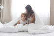 © Tomsickova - Beautiful blond child and his mother, playing at home in the morning in bed, smiling, laughing and having fun
