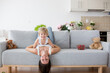 Mother and toddler child, hanging upside down from a couch at home,