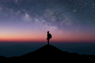 Wall Mural - Silhouette of young traveler and backpack watched the star and milky way alone on top of the mountain with beautiful night sky. He enjoyed traveling and was successful when he reached the summit.