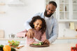 © Prostock-studio - African american father teaching daughter how to prepare salad